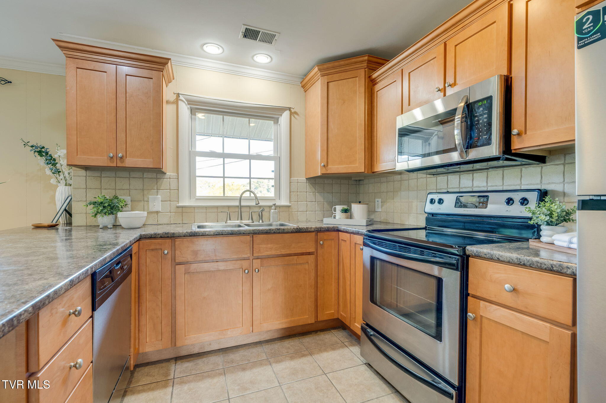 Kitchen with warm wood cabinets, granite counters, and stainless steel appliances.