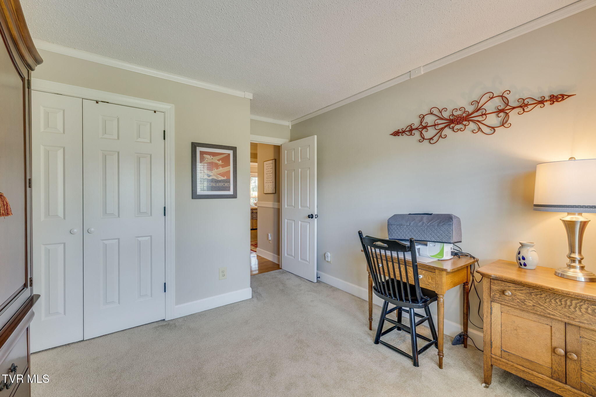 Furnished bedroom workspace with a sewing machine on the desk and double closet doors.