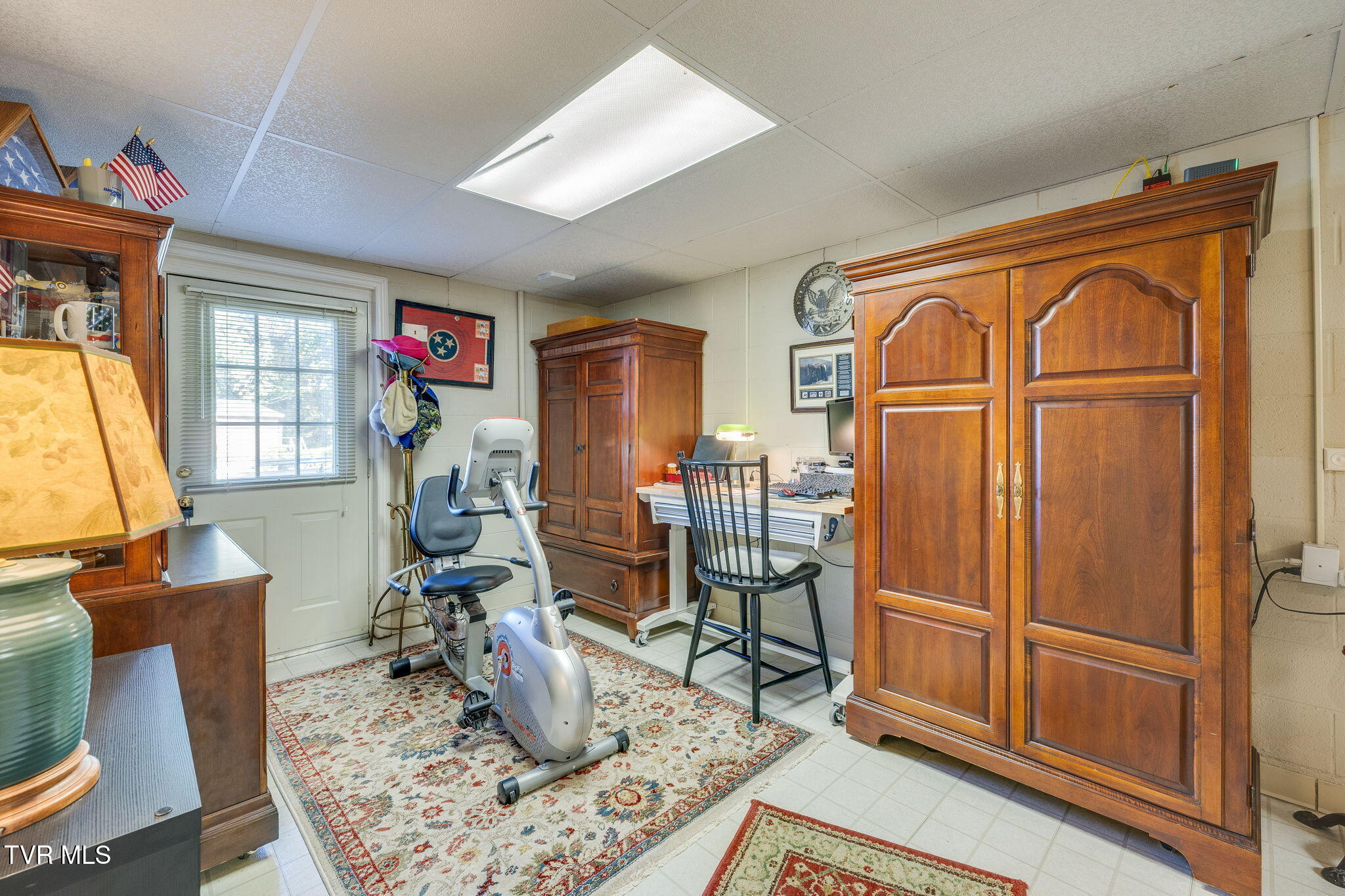 Office and exercise room with a stationary bike, desk, and large carved wooden cabinets.