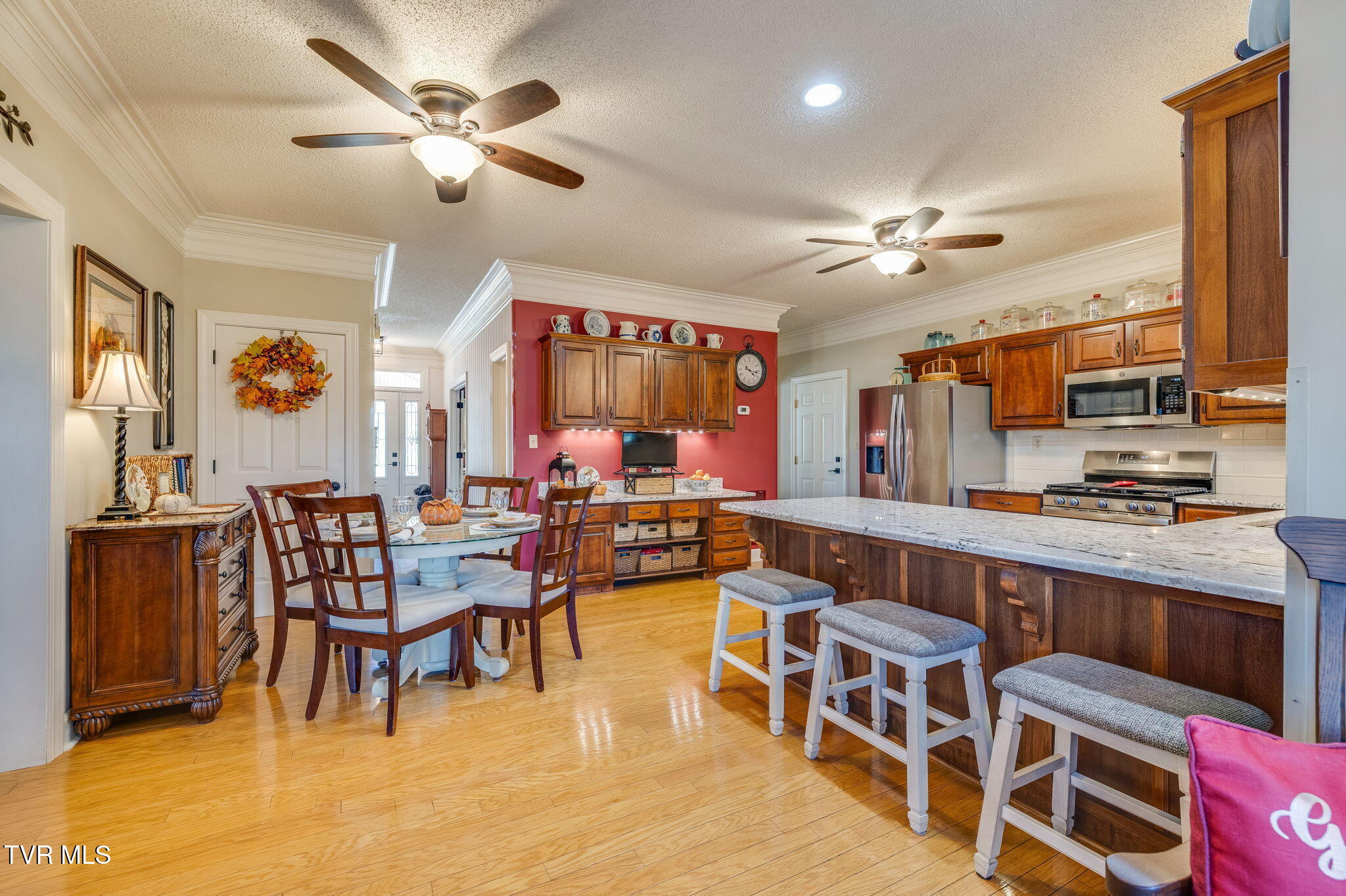 Kitchen and dining area with a granite island, dark wood cabinets, and stainless steel appliances.