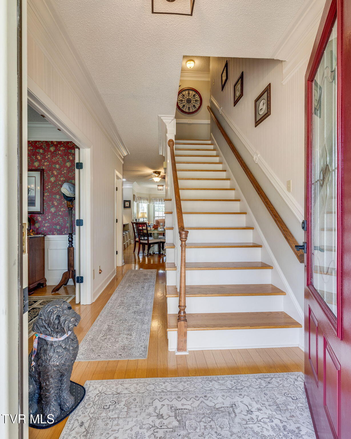 Entryway staircase with white risers, wood treads, and a red glass-paneled front door.