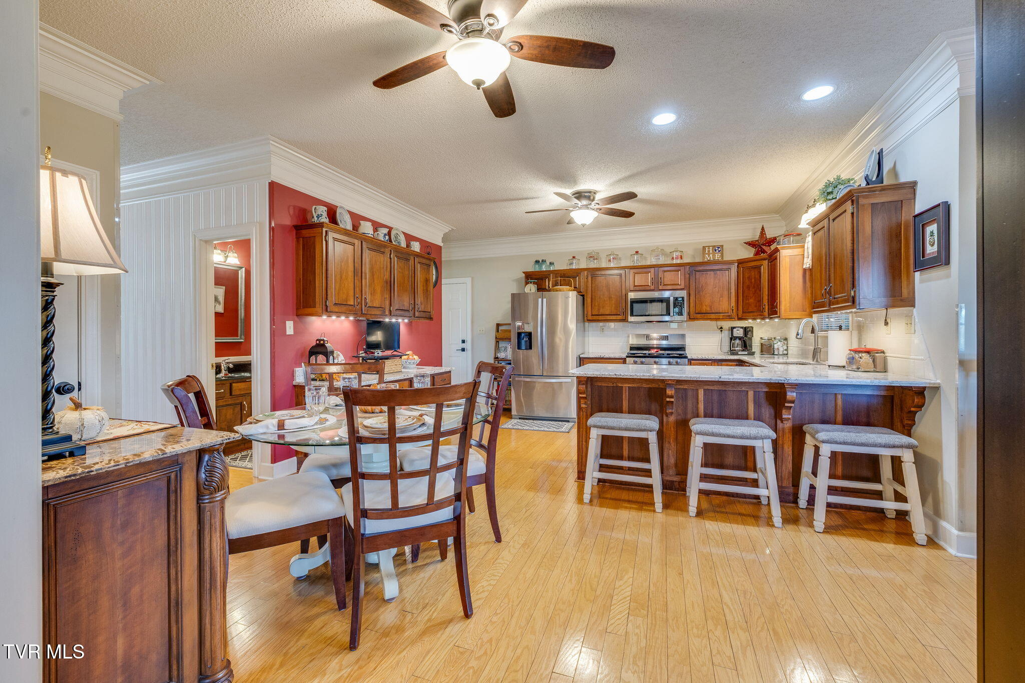 Kitchen with dark wood cabinets, stainless steel appliances, a large island, and an adjacent dining area.