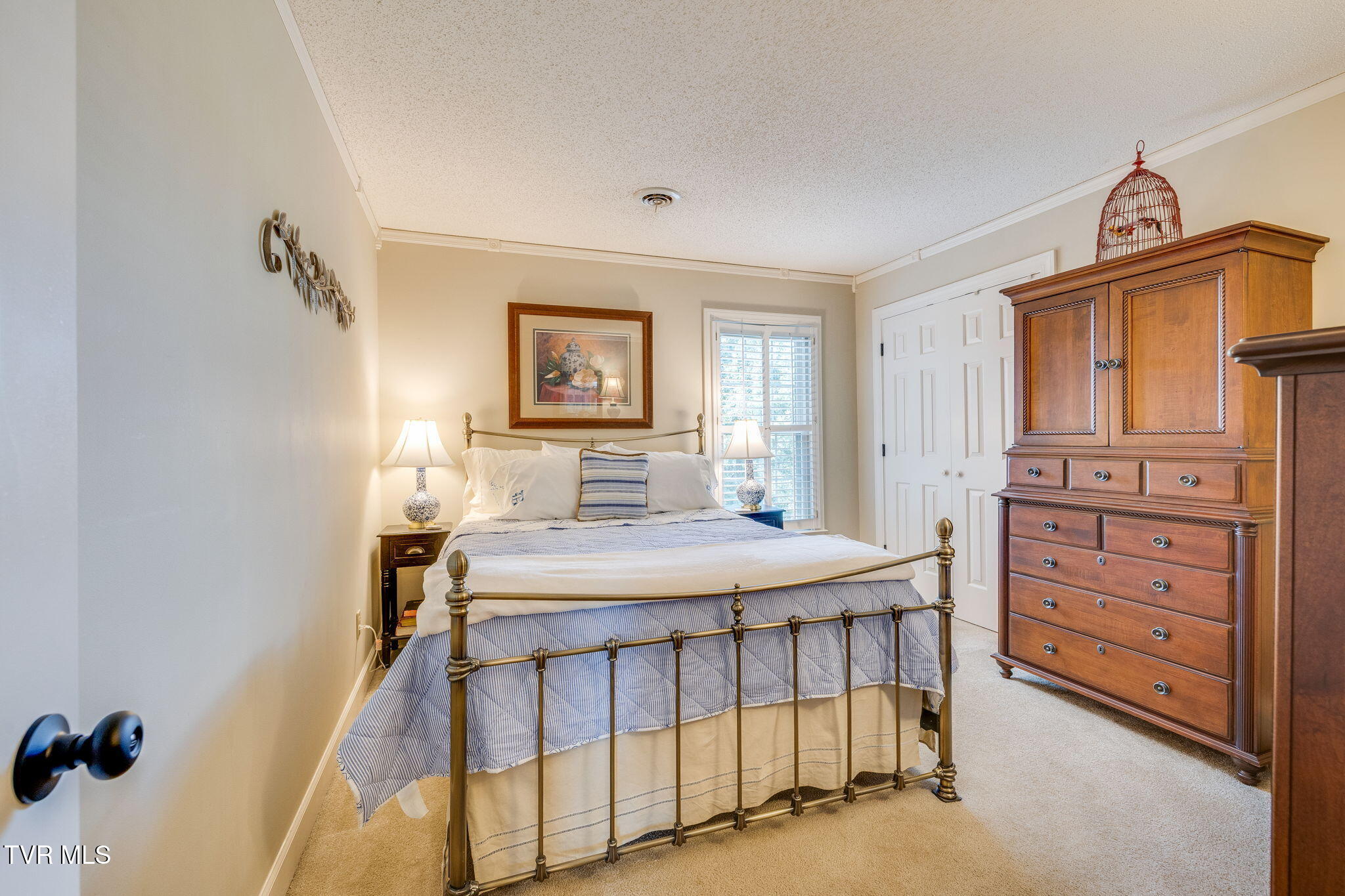 Bedroom with a brass bed, blue-and-white bedding, and a large wooden dresser.