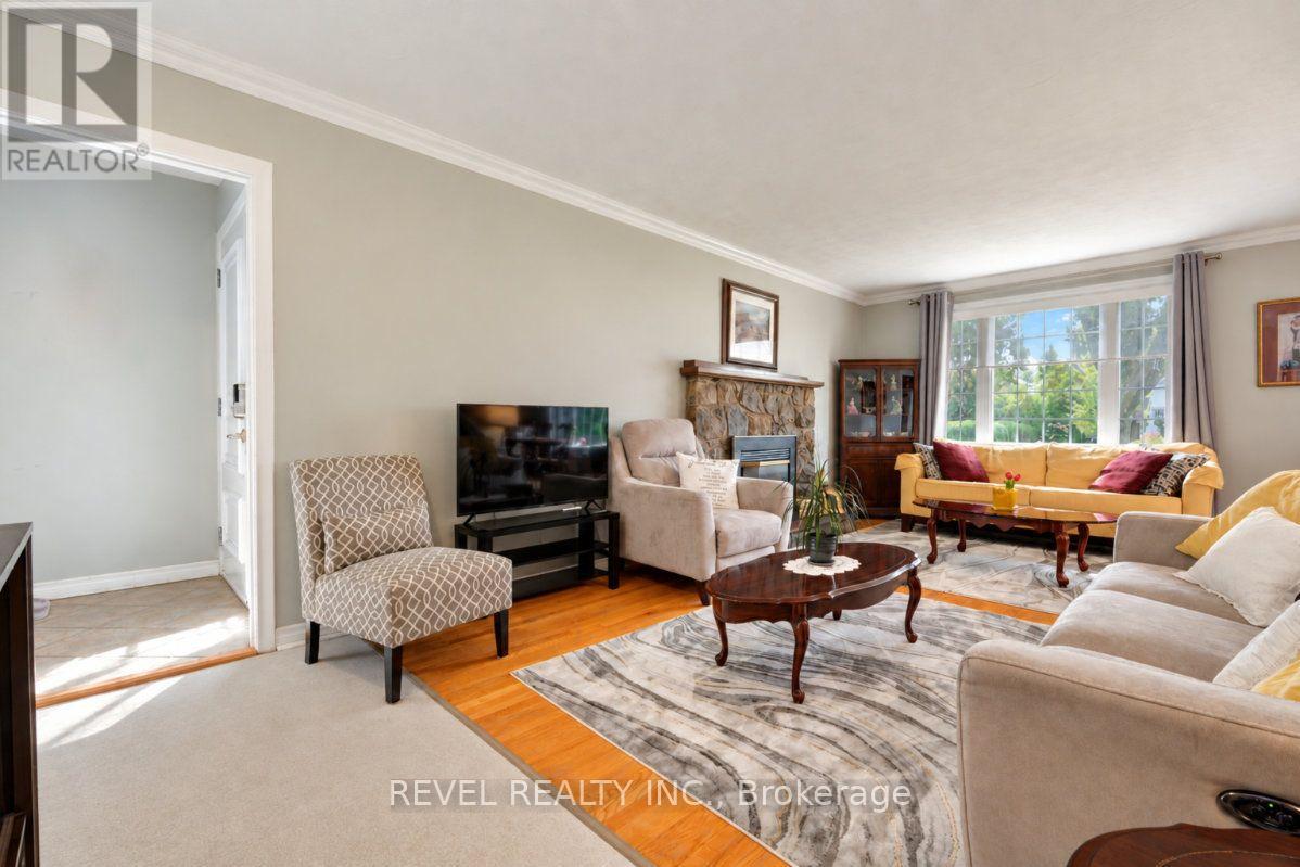 Furnished living room with a stone fireplace, hardwood floors, and large windows.