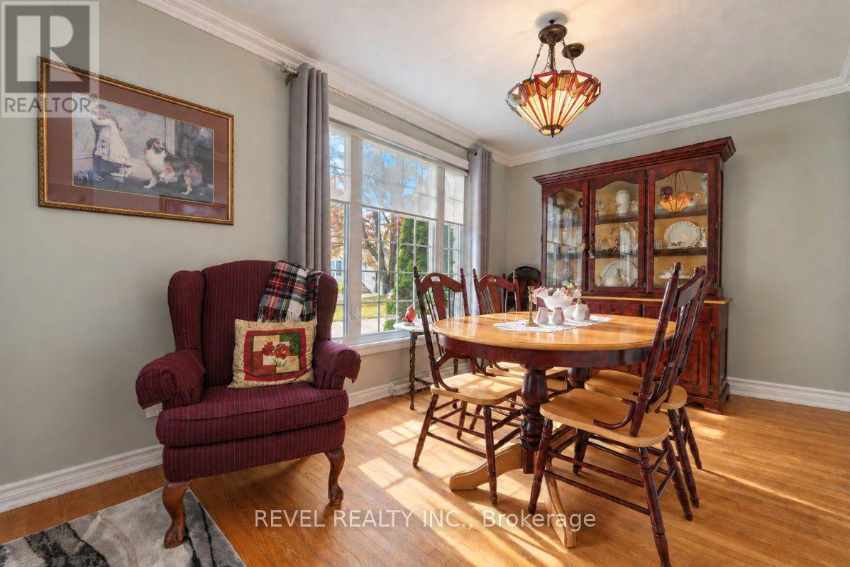 Dining room with an oval wooden table, glass-front china cabinet, and large windows.