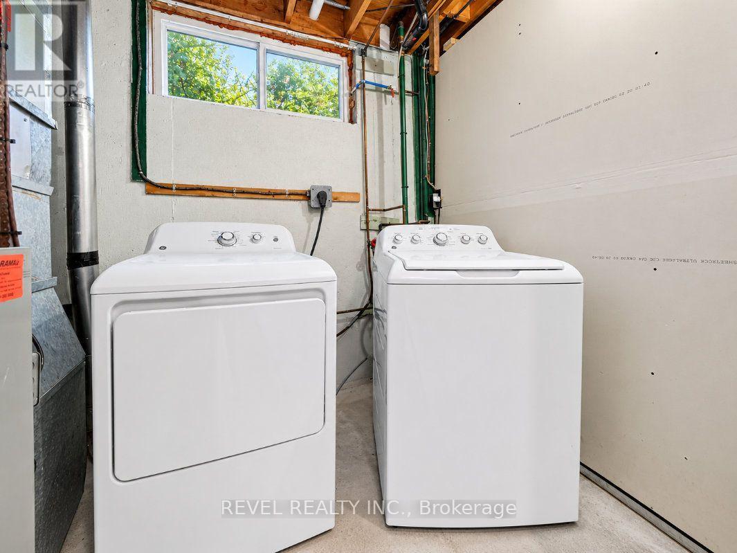 Laundry room with a white dryer and top-loading washer beneath a high window.
