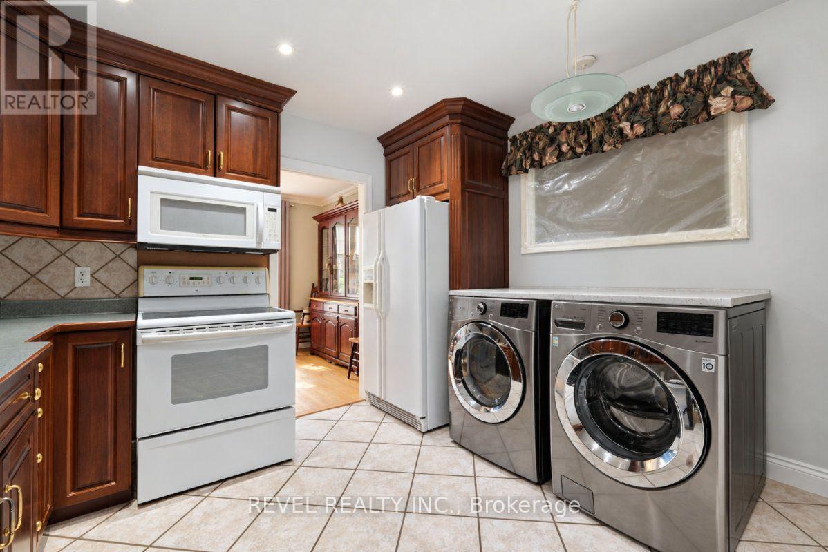 Kitchen and laundry area with dark wood cabinets, white range, and front-load washer and dryer.