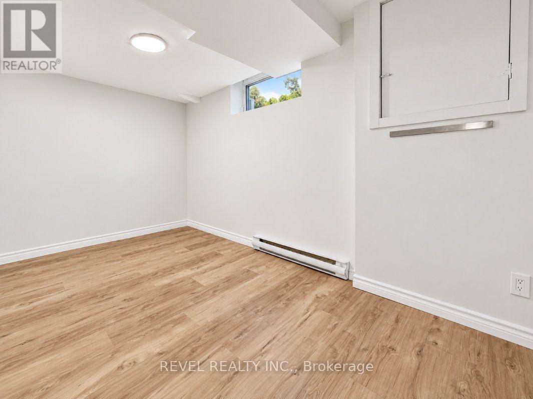 Empty room with wood-look flooring, a narrow high window, baseboard heater, and ceiling access hatch.