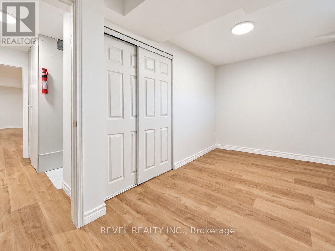Empty room with a paneled sliding closet, light wood-look flooring, and a ceiling light.