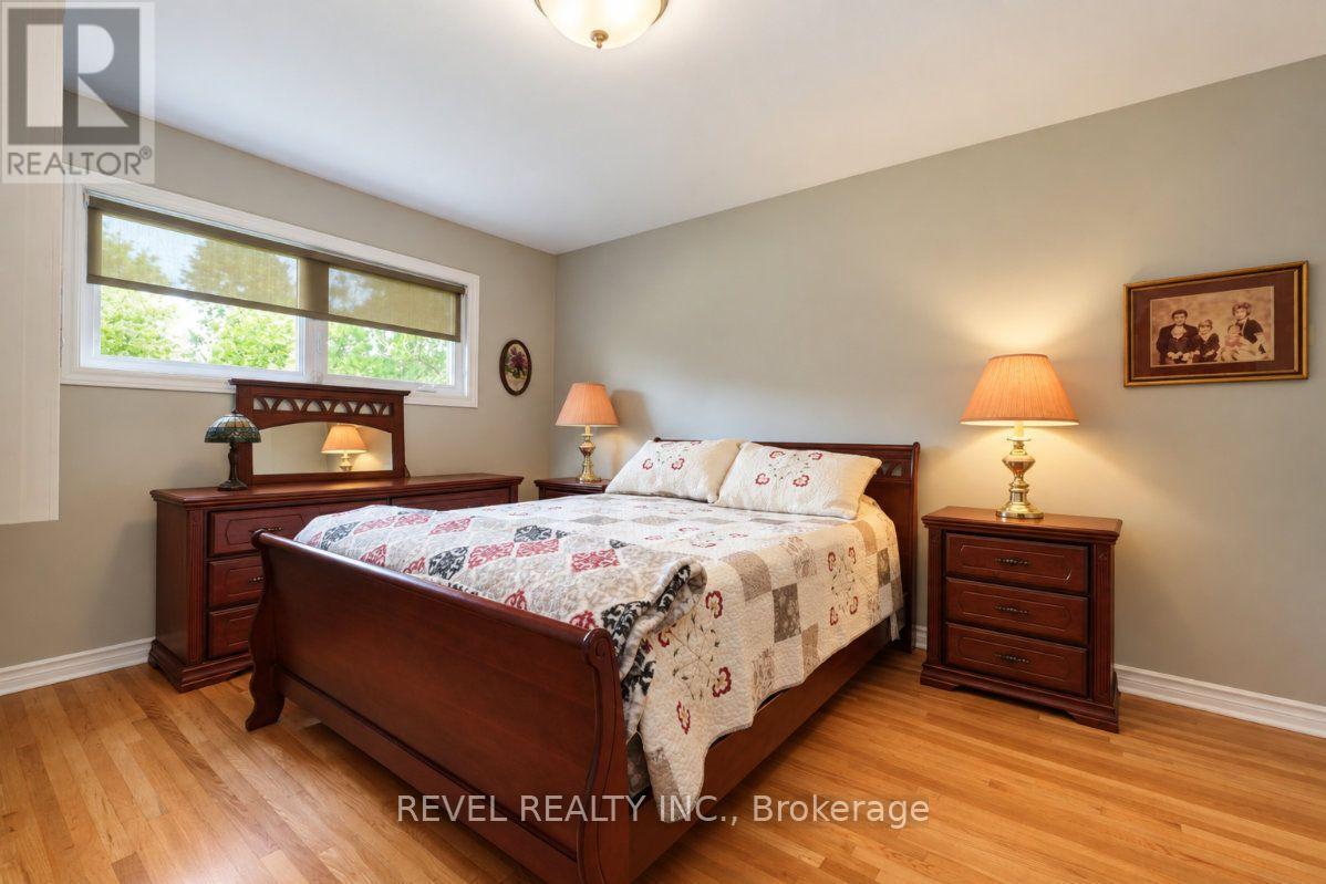 Furnished bedroom with a dark wood bed, patterned quilt, and wide windows.