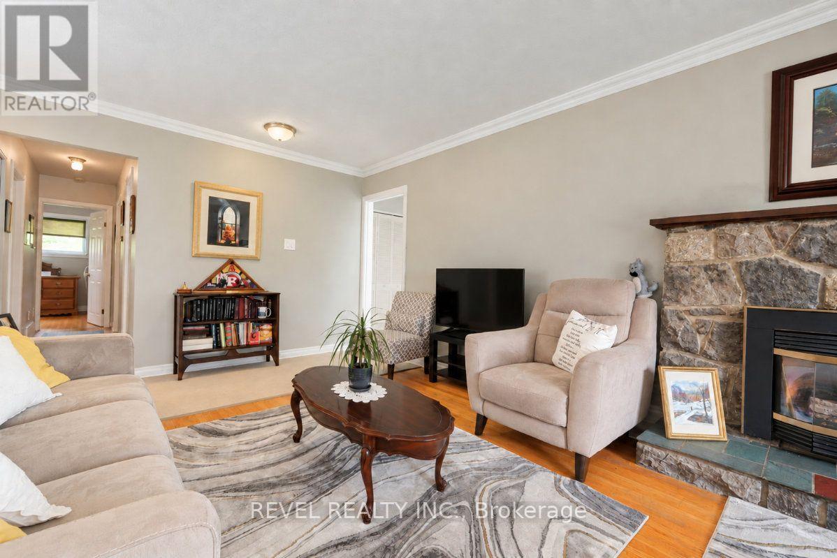Furnished living room with stone fireplace, beige seating, television, and hardwood floors.