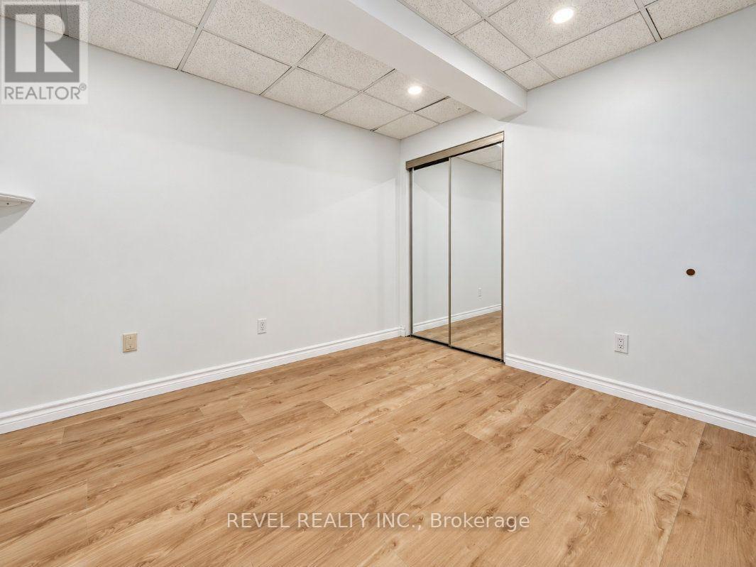Empty room with light wood-look flooring and mirrored sliding closet doors.