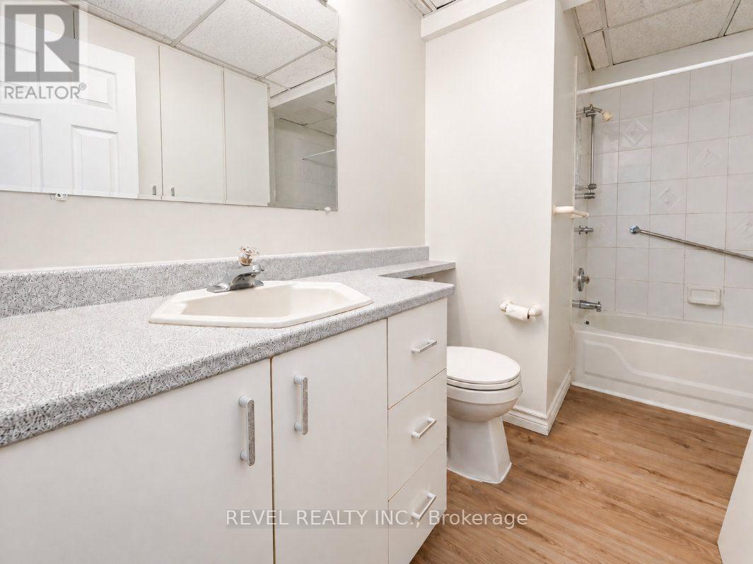 Bathroom with a long white vanity, mirrored cabinets, and tiled tub and shower.
