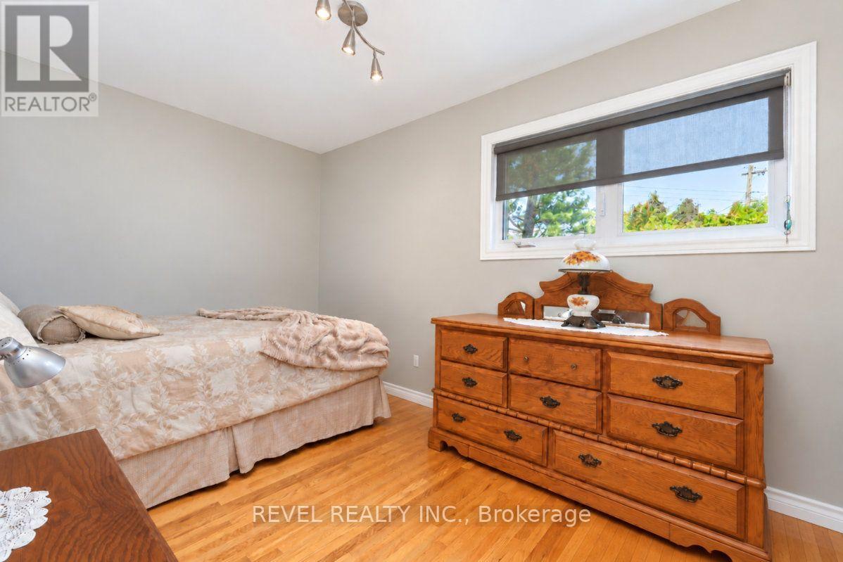 Bedroom with pale floral bedding, a large wooden dresser, and hardwood floors.