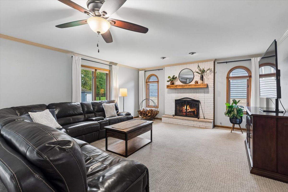Living room with a white brick fireplace, black leather sectional, and arched windows.