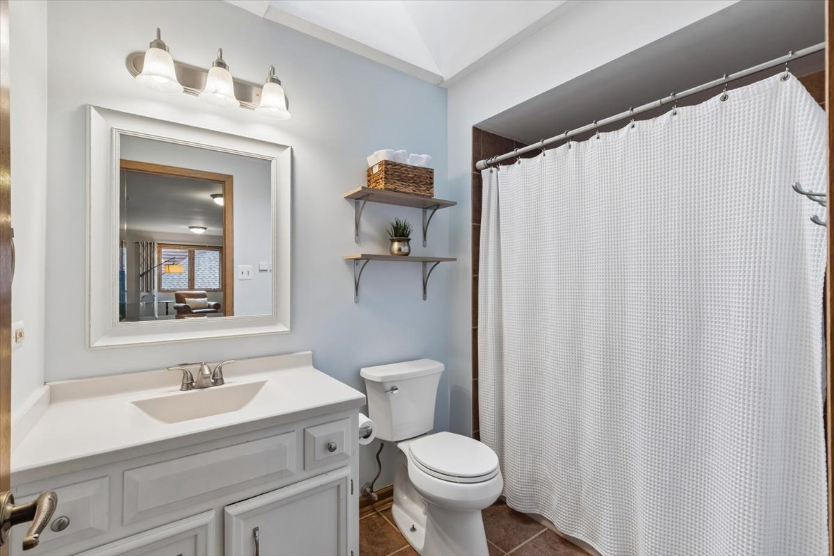 Bathroom with a white vanity, toilet, and shower concealed by a white curtain.