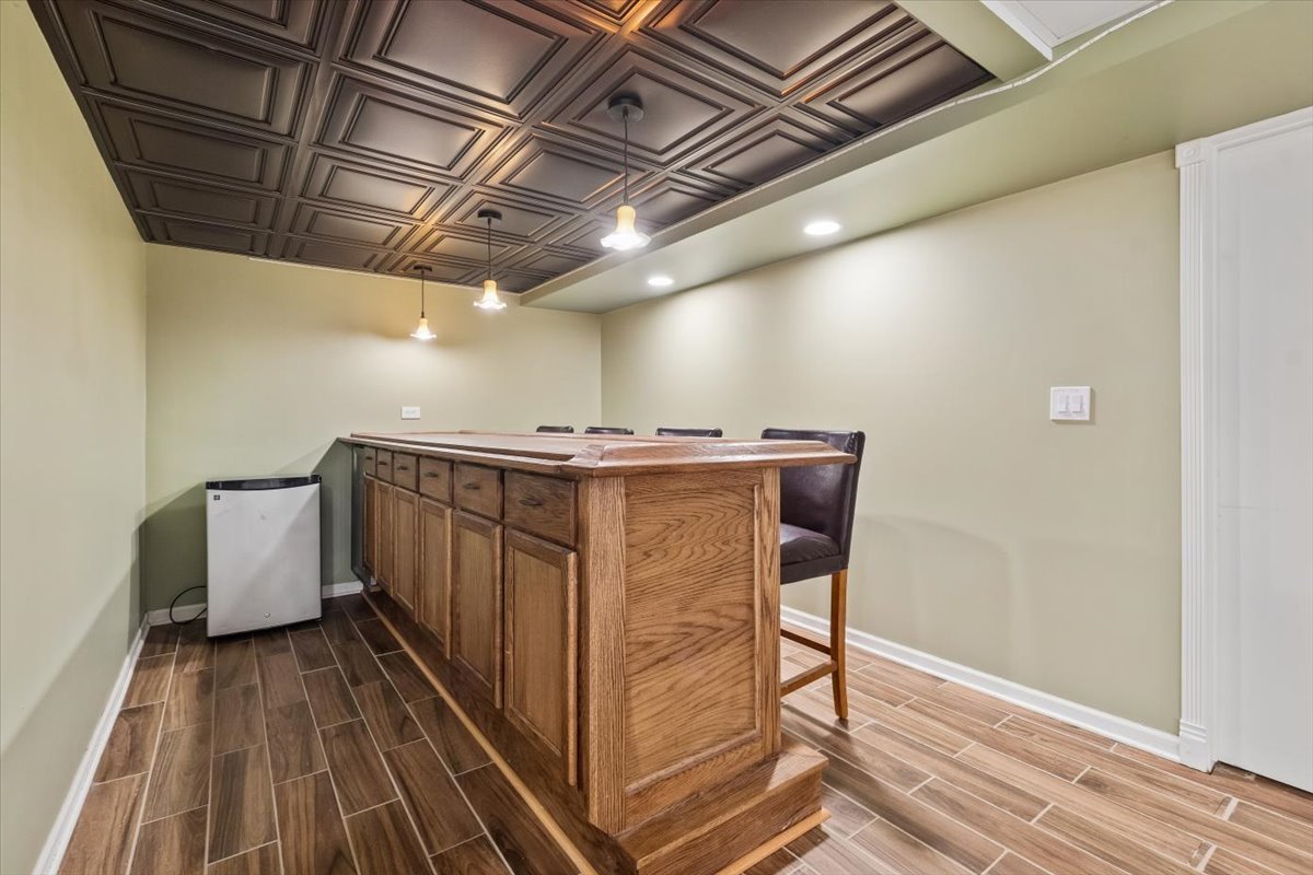 Home bar with a large wood counter, dark stools, and a coffered ceiling.