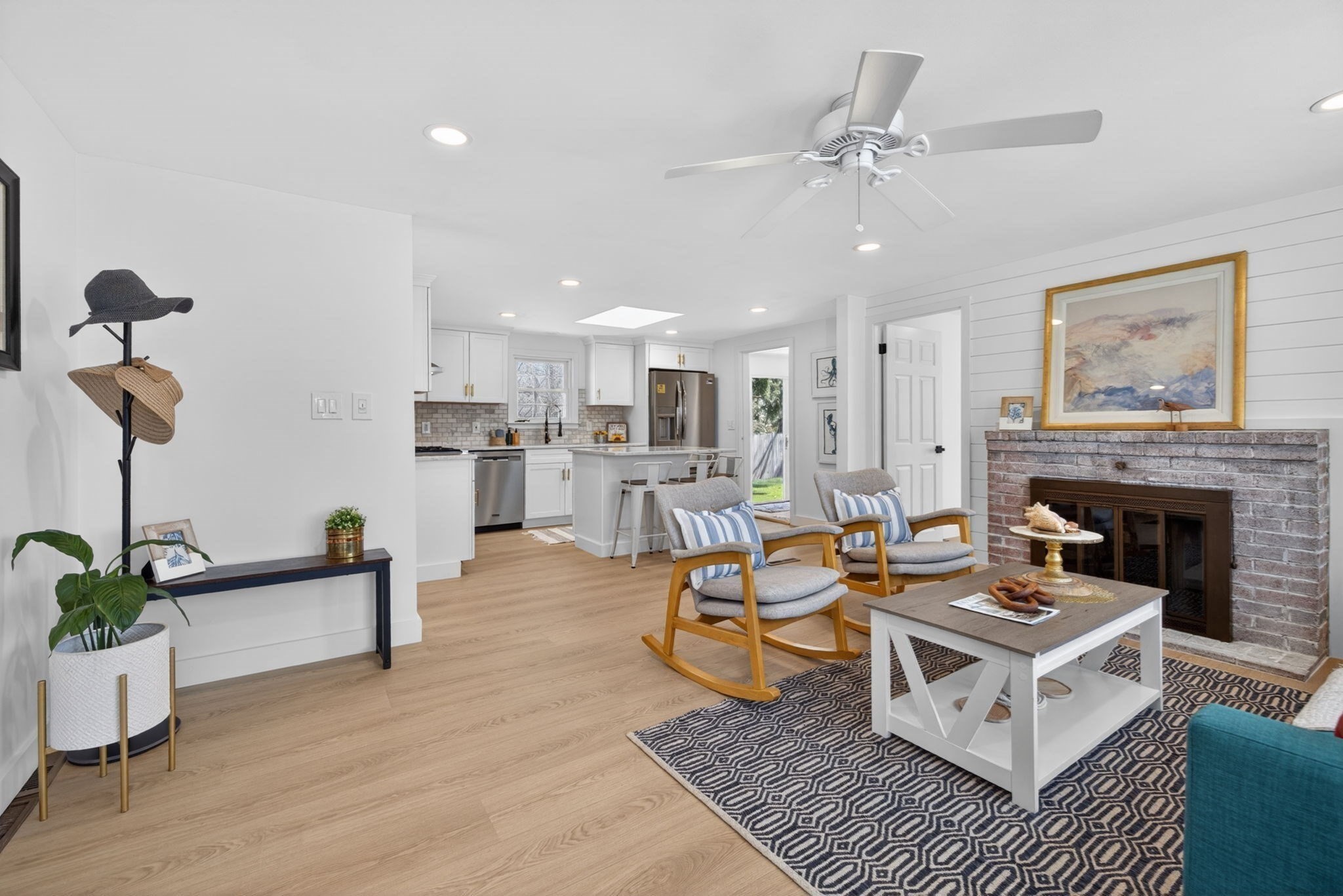 Open-plan living room and kitchen with a brick fireplace and two cushioned rocking chairs.