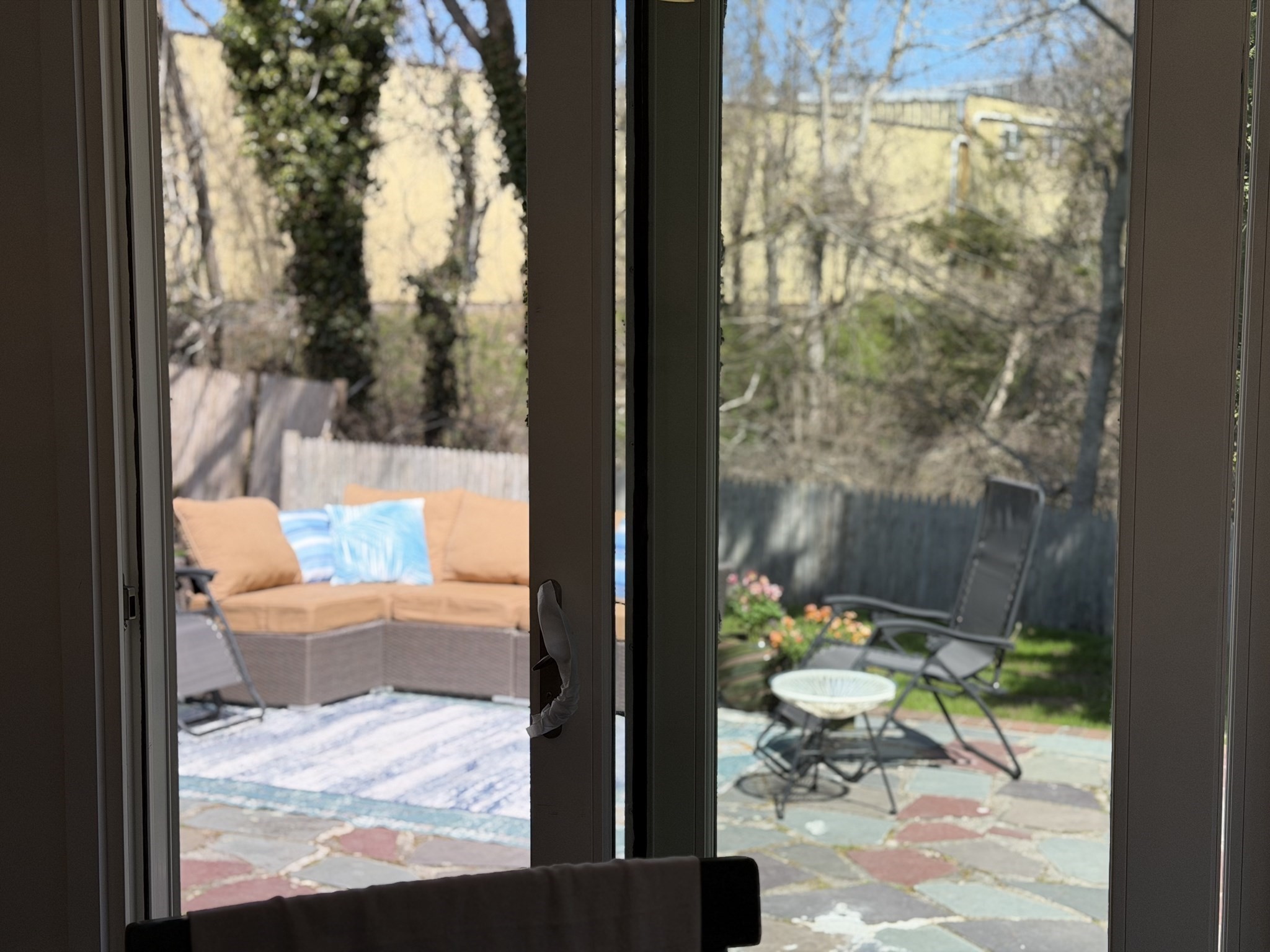 Glass doors open onto a stone patio with a cushioned sectional and outdoor seating.