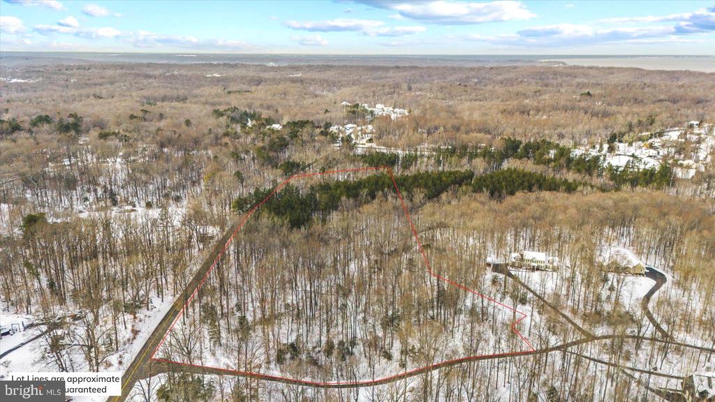 Aerial view of a snow-covered wooded lot with red lines marking its approximate boundaries.