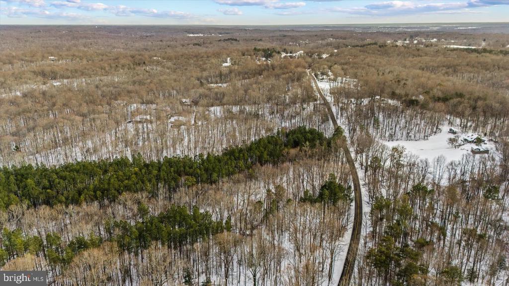 Aerial view of snow-dusted woodland crossed by a winding road.