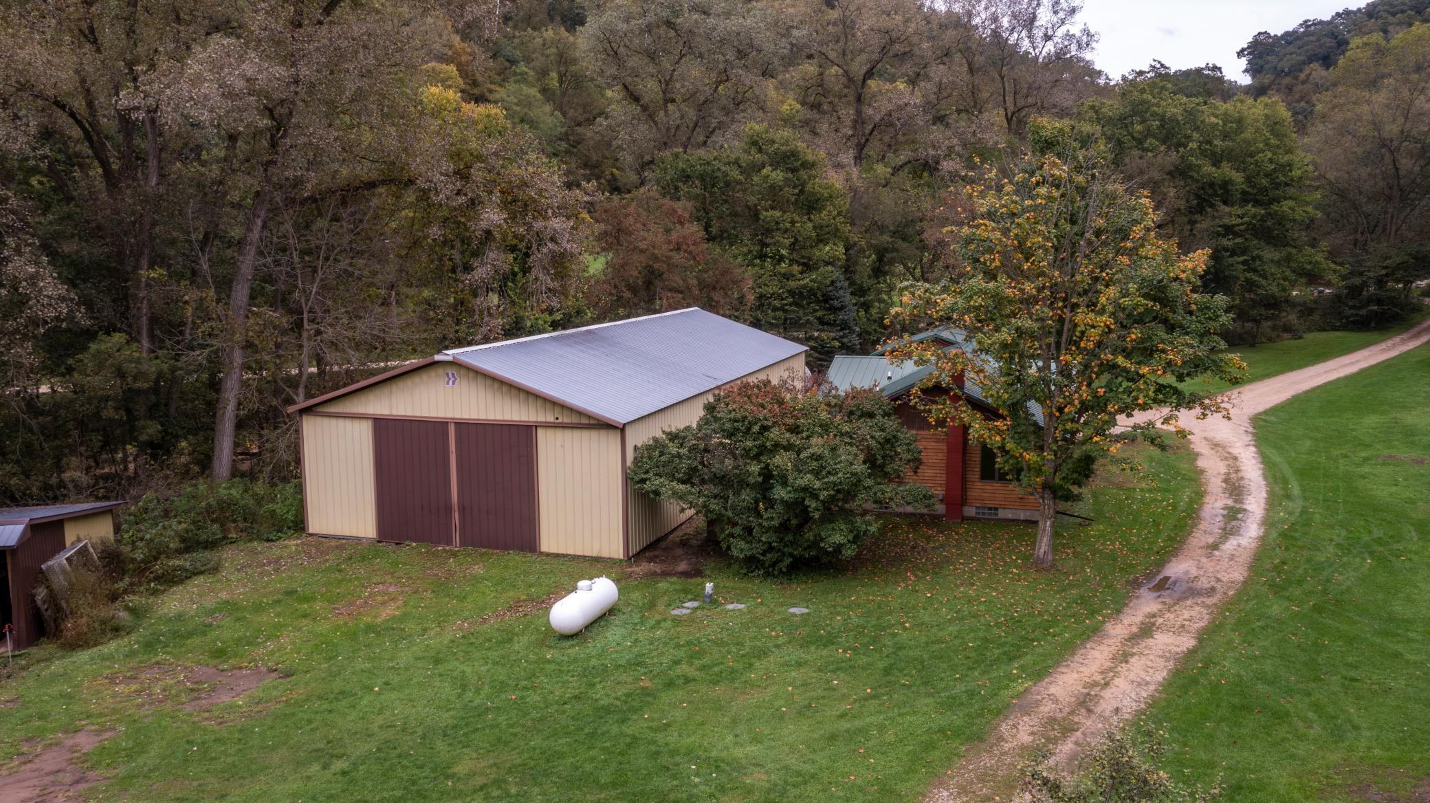 Rural property with a large pole barn, partially visible house, and gravel driveway.