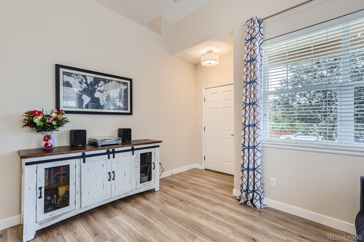 Furnished room with a white media console, turntable, framed world map, and large curtained window.