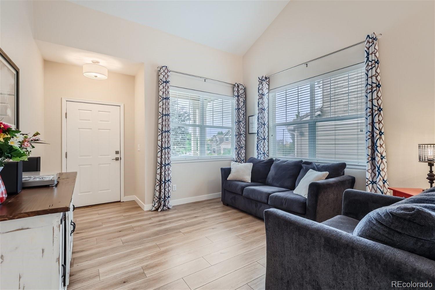 Living room with vaulted ceiling, large windows, and dark gray sofas.