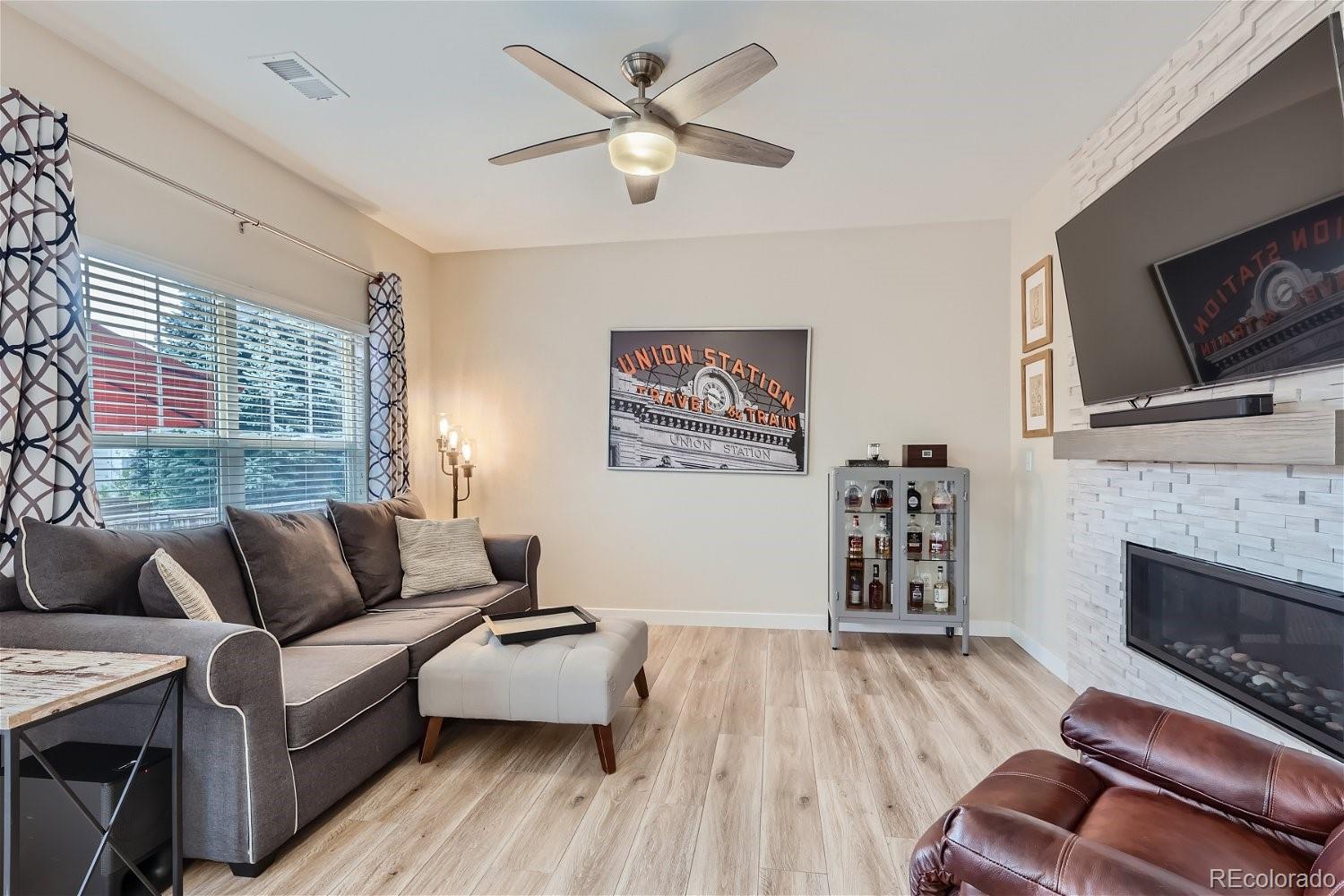 Living room with gray sofa, white tiled fireplace, and wall-mounted television.