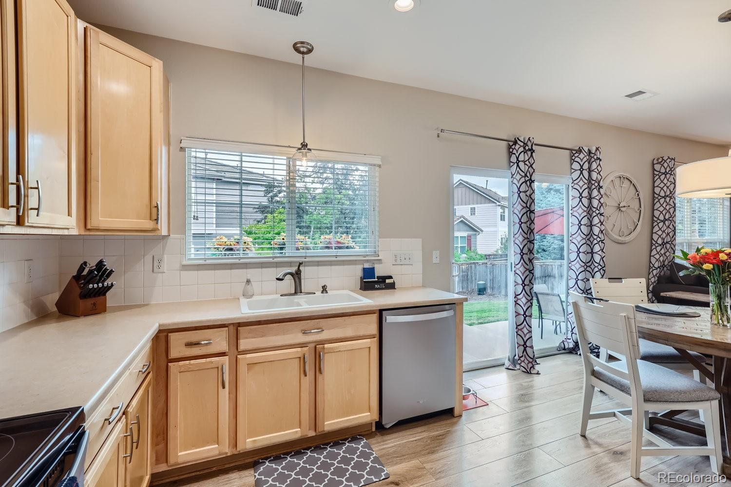 Kitchen with light wood cabinets, a wide window over the sink, and an adjoining dining area.