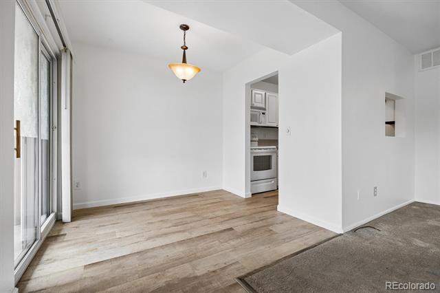 Vacant living area with light wood-look floors, sliding glass doors, and kitchen doorway.