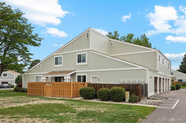 Two-story condominium exterior with a fenced patio and parking spaces.