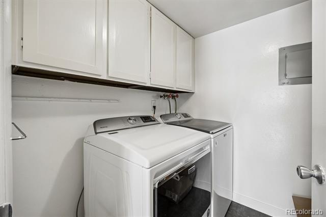 Laundry room with a front-loading washer, top-loading dryer, and white overhead cabinets.