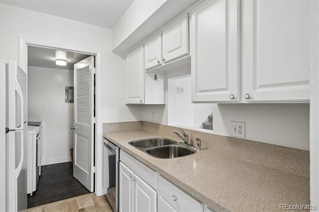 Kitchen with white cabinets, a double-basin sink, and an open door to the laundry area.