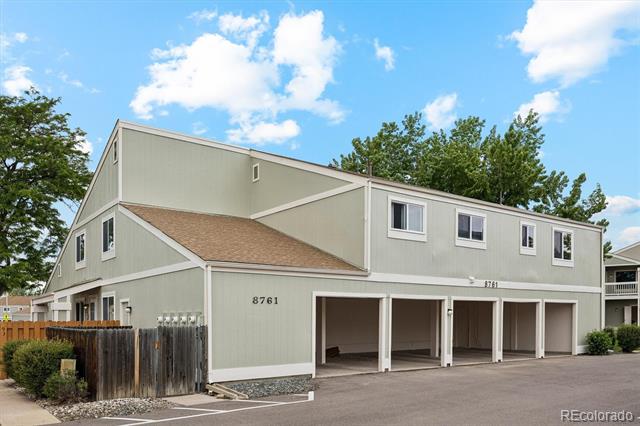 Pale green two-story townhouse exterior with open garage bays and the number 8761.