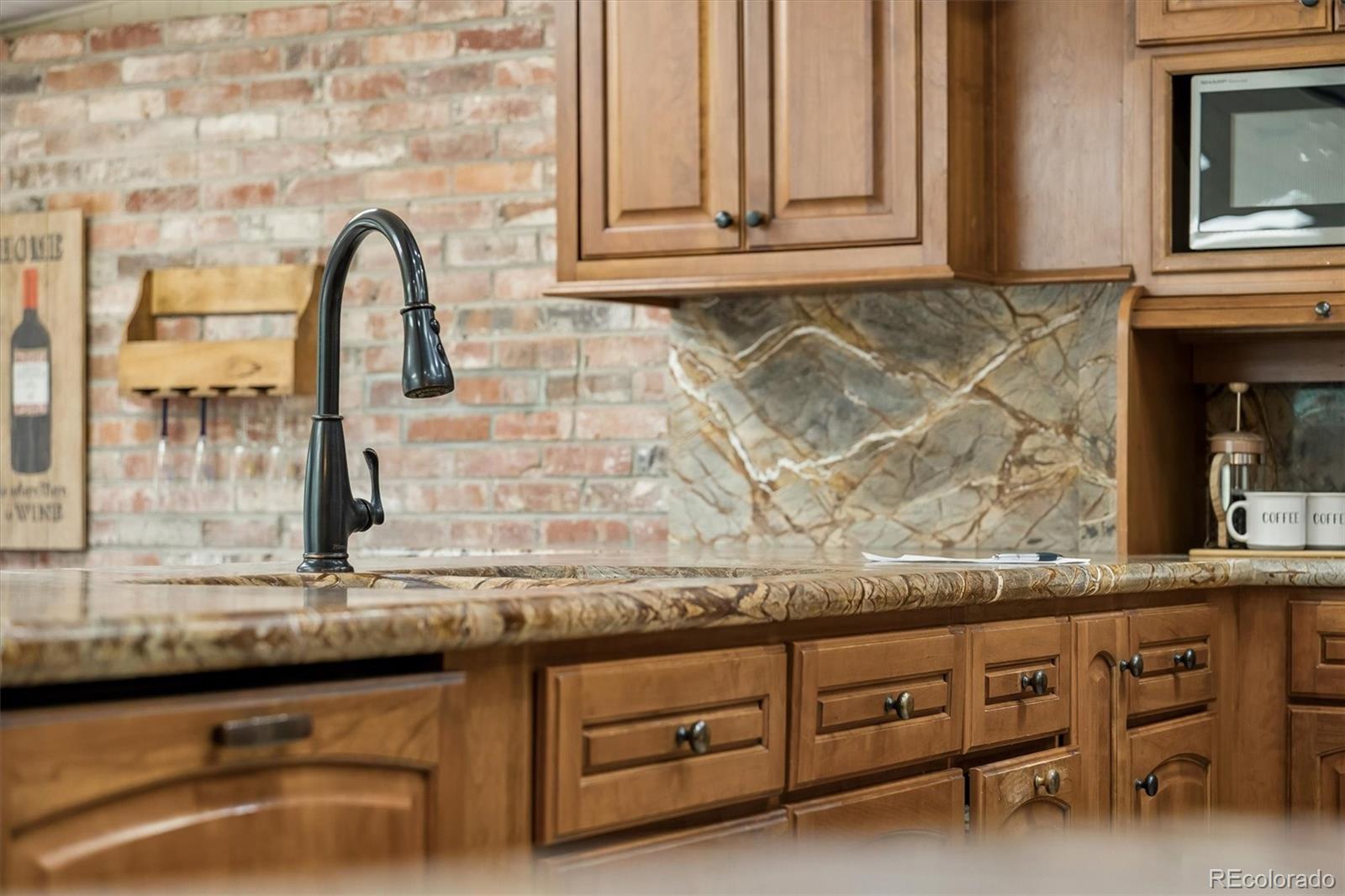 Kitchen with warm wood cabinets, veined stone counters, and a black gooseneck faucet.