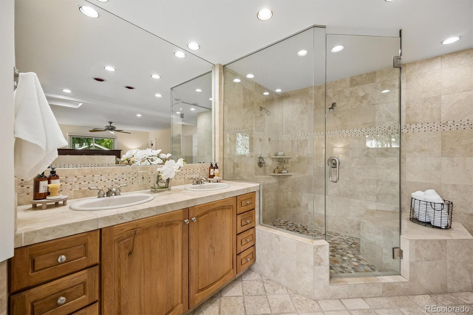 Primary bathroom with a double-sink wood vanity and a large glass-enclosed tiled shower.