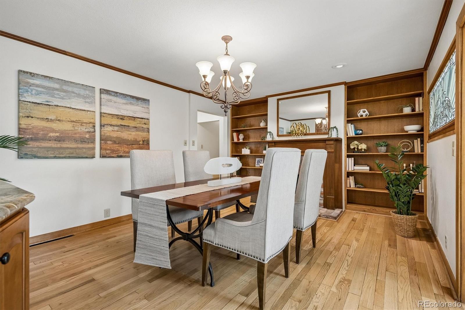 Dining room with built-in wood shelving, a dark table, upholstered chairs, and hardwood floors.