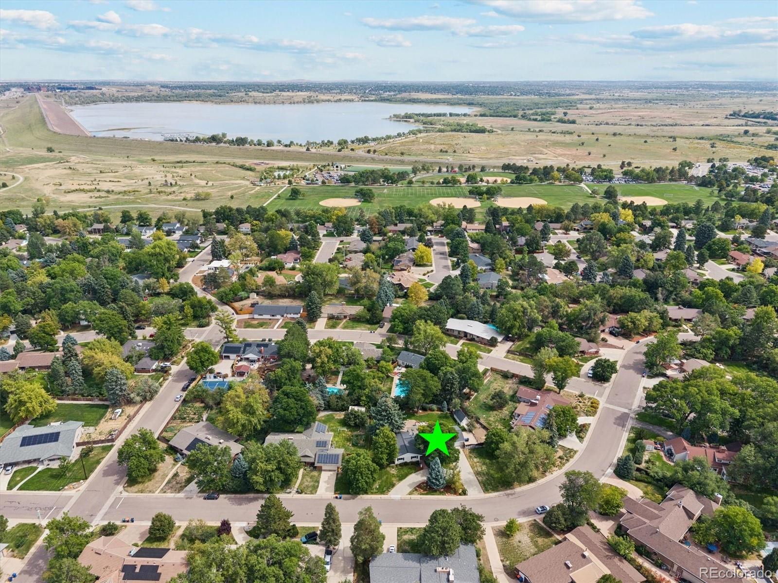 Aerial view of home marked by a green star, near reservoir and baseball fields.