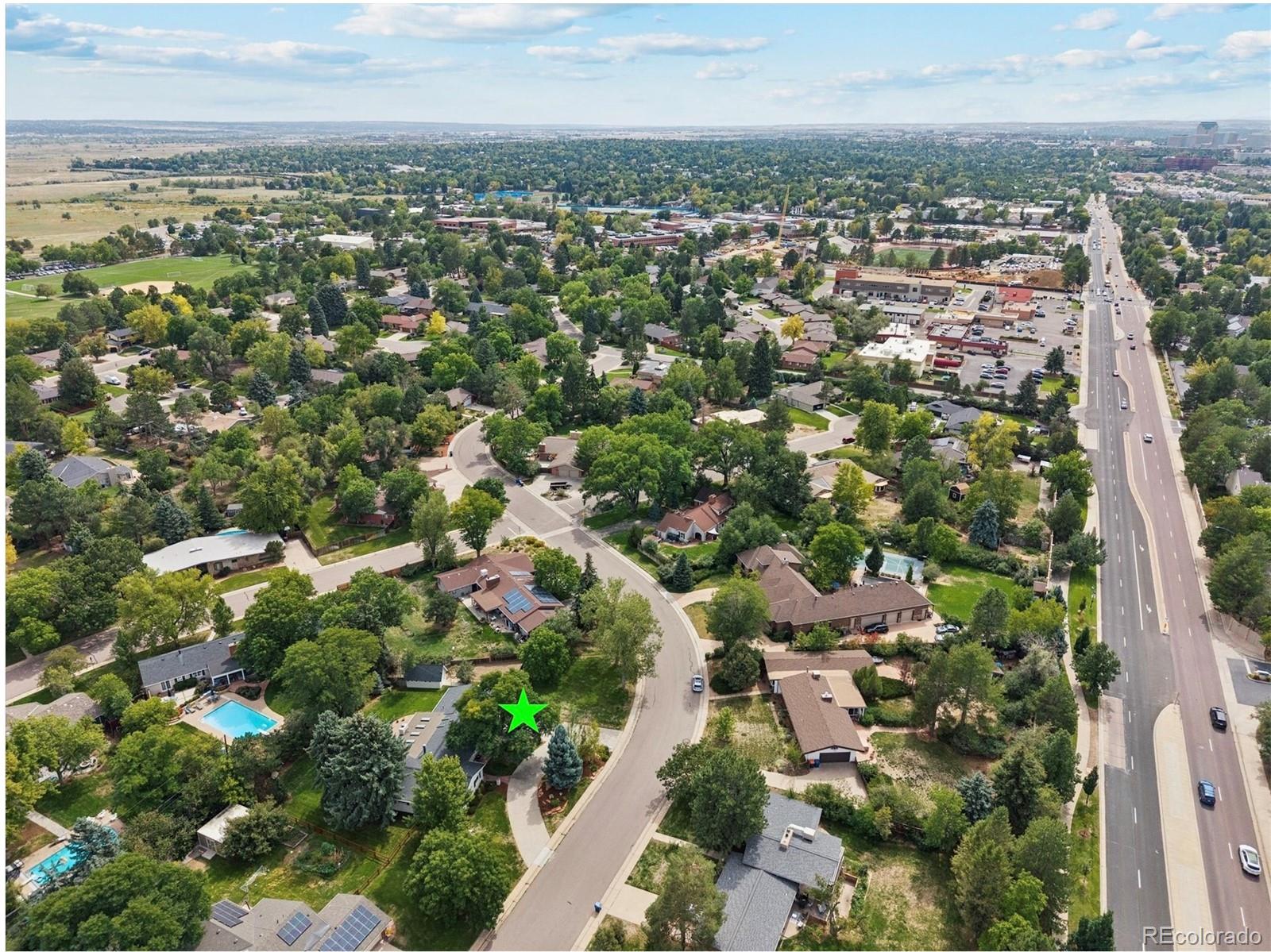 Aerial view of a tree-lined neighborhood, with the featured property marked by a green star.