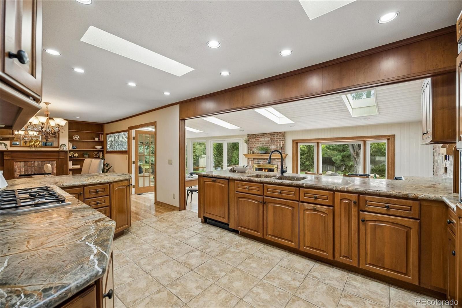 Spacious kitchen with wood cabinetry, granite counters, a large island, and skylights.
