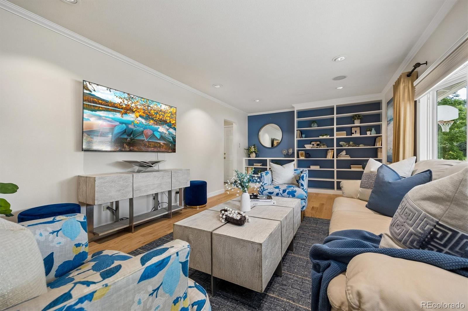 Staged living room with blue accent wall, built-in shelves, and blue-and-white seating.