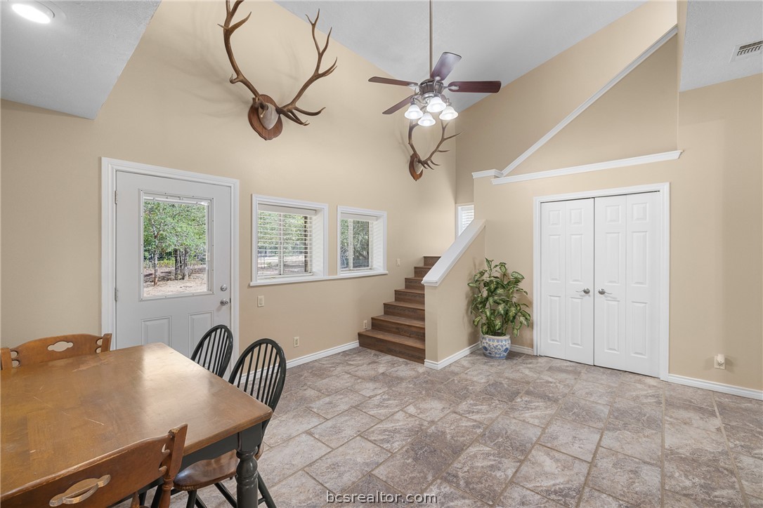 Dining and entry area with tiled floors, a staircase, and mounted antlers.