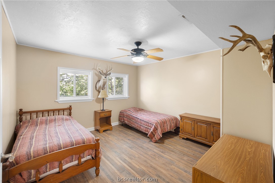 Bedroom with two twin beds, striped bedding, wood furniture, and mounted deer heads.