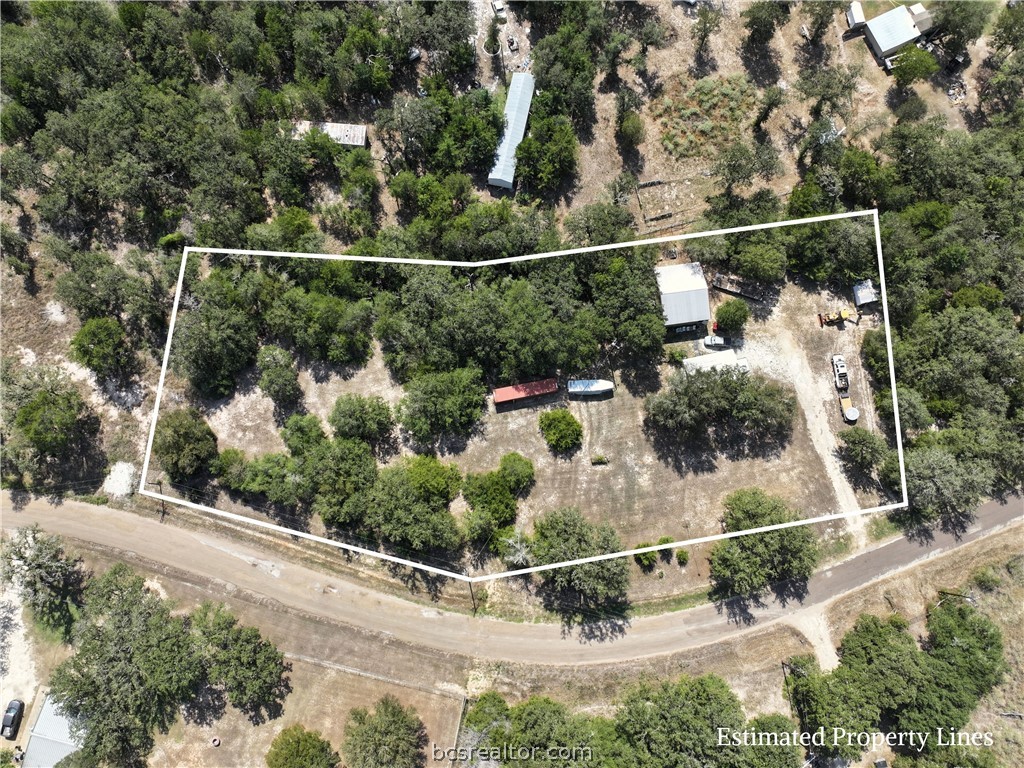 Aerial view of a wooded rural property outlined in white, with clearings and small structures.