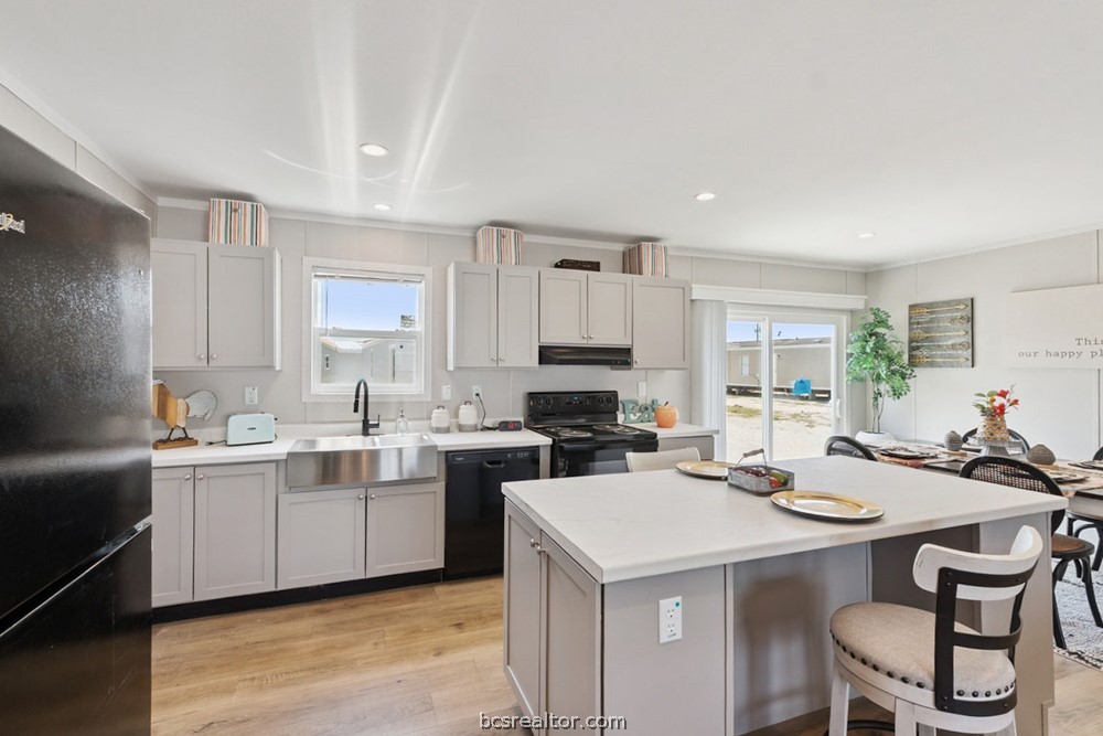 Kitchen with a large white island, farmhouse sink, and glass doors opening to the yard.