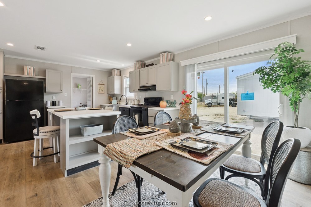 Kitchen and dining area with a white island, set table, and sliding doors overlooking a white outbuilding.