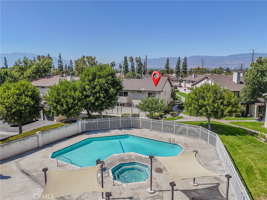 Aerial view of a condo community pool and spa, with homes and mountains beyond.