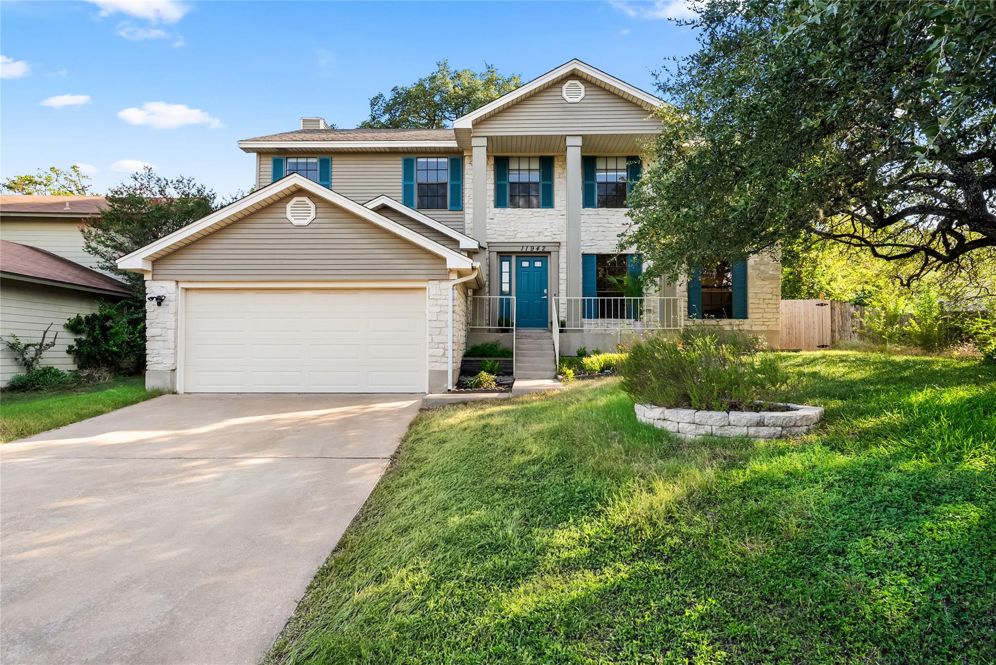Two-story home with teal shutters and door, stone accents, and an attached garage.