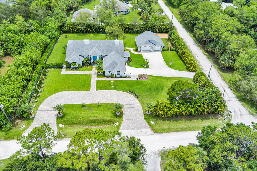 Aerial view of a home and detached garage surrounded by tropical landscaping.